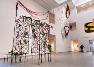 Floral installation with suspended frames and vines in an art gallery.