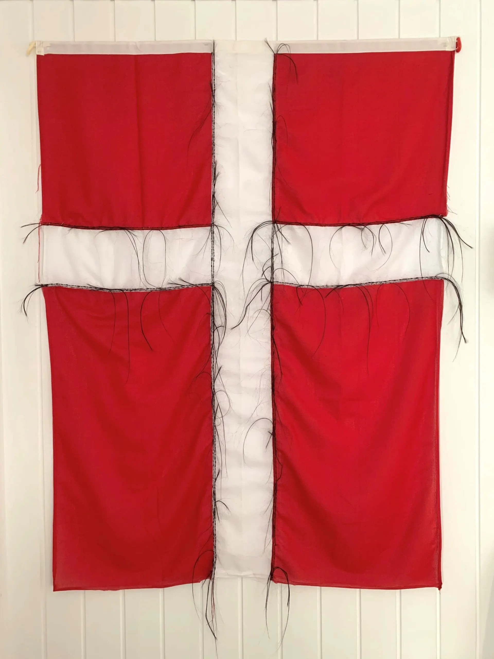 Julie Edel Hardenberg (Greenland, born 1971), Oqaluttuarisaaneq / History , 2019, nylon flag, human hair, 57 1/16 x 43 5/16 inches. Private collection. © Julie Edel Hardberg