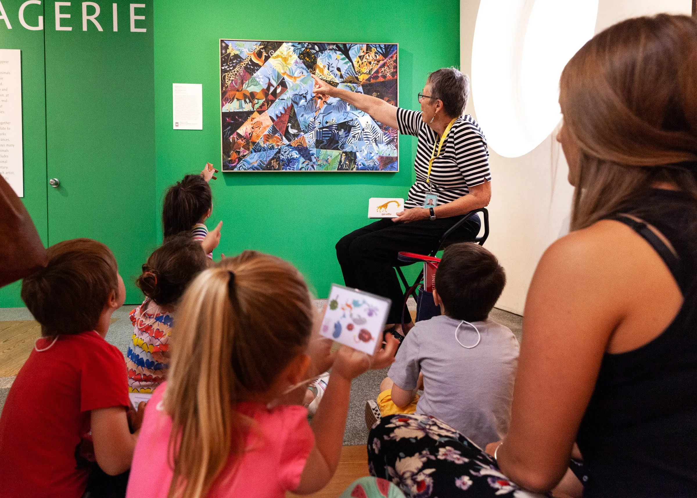 Senior woman teaching children about art in a gallery.