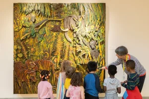 Teacher guiding children viewing a colorful jungle-themed artwork in a museum.